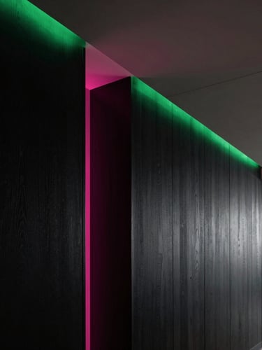 Architectural detail of a luxury residence hallway, black wood paneling, recessed linear lighting with a sharp magenta accent, minimalist ceiling integration