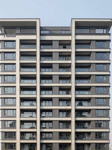 Wide architectural elevation of a modern, multi-family residential building in clean morning light. Straight-on structural angle, concrete and steel detailing, neutral overcast sky, no people, high-end editorial real estate photography.