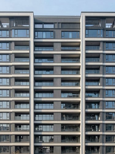 Wide architectural elevation of a modern multi-family residential building, clean straight-on structural lines, crisp morning daylight, no people.