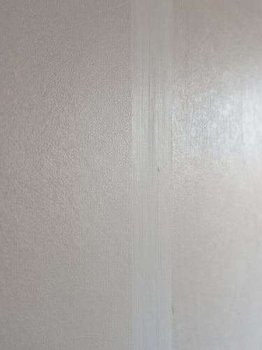 Macro shot of finished drywall showing a seamless blend between knockdown texture on the left and new matching application on the right