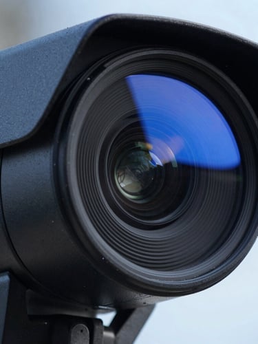 Close-up of a high-definition security camera lens with an electric blue status light reflecting on clean black casing, sharp focus, technical style.