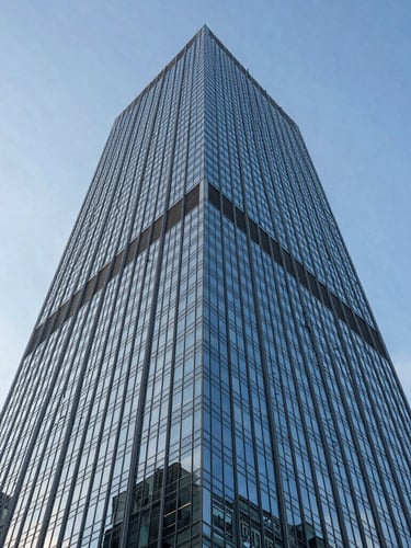 Architectural low-angle shot of a towering modern corporate skyscraper in Mexico City, clean blue glass facade reflecting the morning sky, sharp geometric lines.