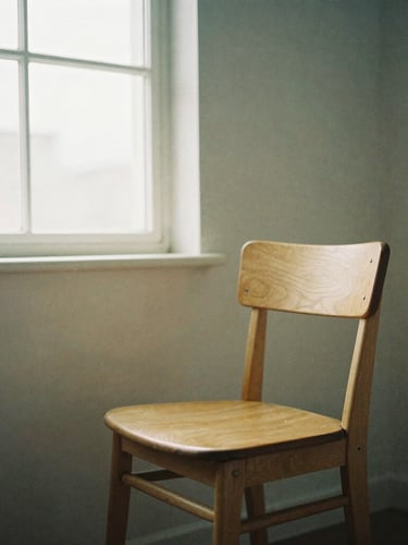 Quiet studio interior with a single oak chair, soft north-facing daylight filtering through a window, muted beige and dusty blue tones, 35mm film texture.