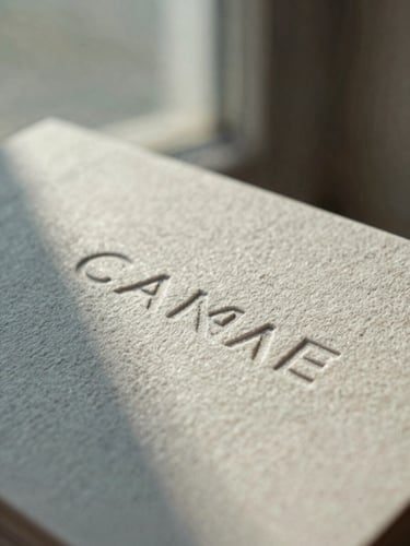 Macro close-up of tactile linen paper business cards with embossed typography, soft diffused north-facing window light, muted dusty blue shadows, editorial 35mm film texture.
