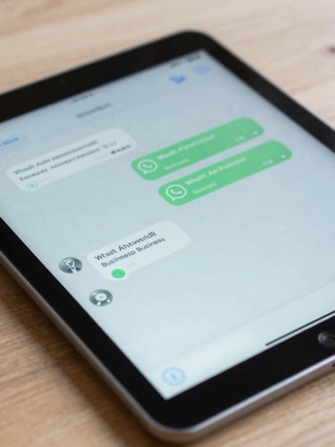 Close-up of a tablet displaying a clean WhatsApp business chat interface on a wooden desk, bright natural daylight, cool blue and slate tones, sharp focus.