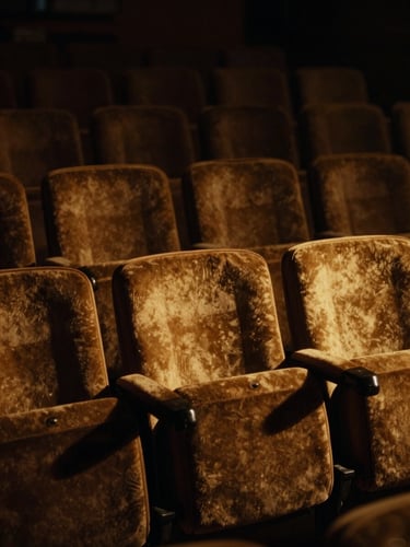 Dramatic low-key cinematic film still, rich shadows, warm golden light catching empty velvet theater seats, 35mm anamorphic lens