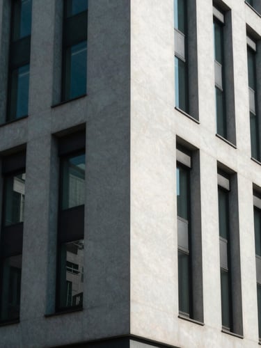 Sharp architectural angle of a modern minimalist corporate building facade under cool, high-contrast indirect daylight, casting geometric shadows.