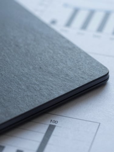 Macro detail of high-quality financial paper reports with sharp architectural shadows, cool diffused daylight, desaturated slate tones