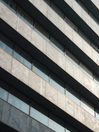 Abstract architectural lines of a modern corporate building, sharp geometric shadows, cool diffused daylight, premium editorial feel.