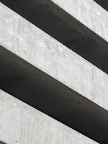 Macro shot of clean, sharp architectural concrete lines with dramatic shadows, cool diffused daylight, representing structure and corporate stability.