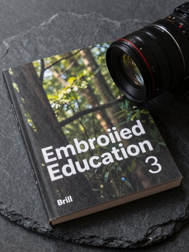 High-resolution cover of the book 'Embodied Education' published by Brill, resting on a dark slate surface, soft natural side lighting.