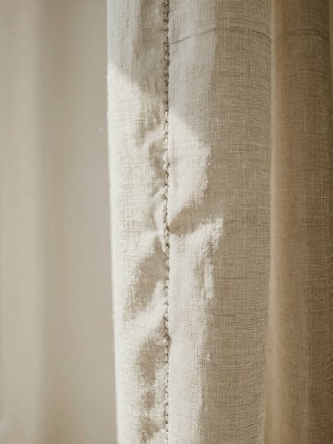Extreme macro shot of heavy Belgian linen fabric texture, catching soft morning light, showing double-stitched seams