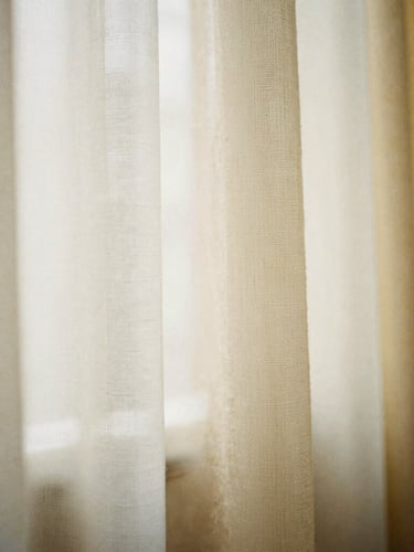 Macro photography of raw textile swatches in ivory, warm beige, and soft gold, soft morning window light, high-texture weave, medium format film