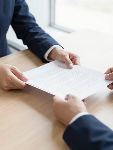 Close-up of professional business consultation, hands reviewing secure financial documents on a wooden table, bright natural daylight, sharp focus.