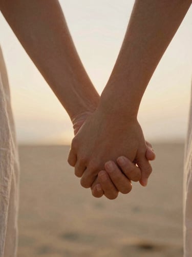 Intimate cinematic close-up of a couple holding hands during golden hour, warm backlight, soft focus on fingers, 35mm film grain, sand tones