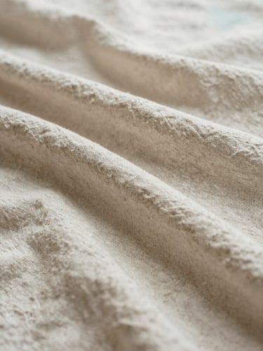Close-up of soft beige linen fabric texture, natural light creating gentle organic folds, serene and calming atmosphere