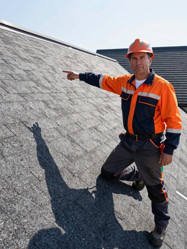 Portrait of an experienced roofer, mid-40s, in branded gear, pointing confidently at a perfectly installed asphalt shingle. Bright morning light, sharp architectural photography.