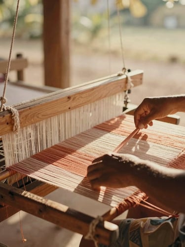warm editorial photography, soft natural golden-hour light, muted sun-washed tones, shallow depth of field, 35mm. A local artisan weaver working on a wooden loom in a sunlit workshop in Uruburetama, threads of terracotta and cotton catching the warm afternoon light.