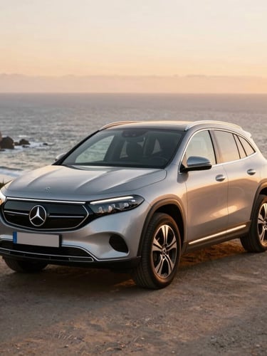 A sleek silver Mercedes Benz EQA250 parked near a coastal viewpoint in Sintra, warm sunset light reflecting on the polished chassis, Atlantic ocean in the background.