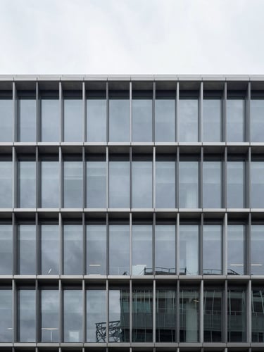 Minimalist architectural photography of a modern steel and glass corporate building facade, cool overcast daylight, deep charcoal and silver tones, sharp focus, 35mm