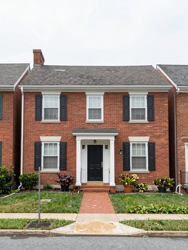 A straight-on exterior shot of a charming brick townhouse in a quiet Maryland neighborhood, soft overcast daylight, realistic and un-staged, 35mm lens