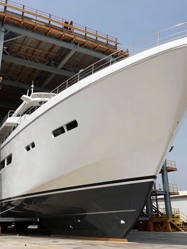 Crisp high-contrast natural daylight shot of a massive modern yacht hull under construction inside a clean, structured dry dock, architectural lines, geometric steel frames