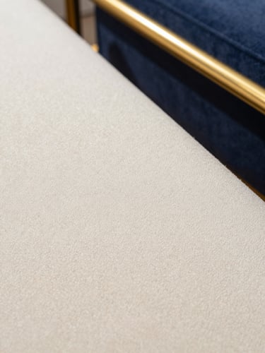Macro photograph of pristine, clean cream bouclé fabric texture, soft architectural light, gold accent details, sharp focus