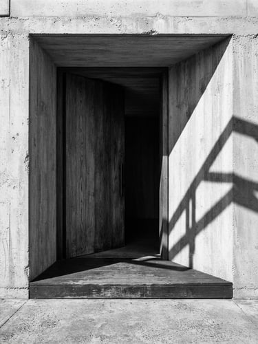 Stark architectural photography of a massive raw concrete threshold, harsh natural sunlight casting deep geometric shadows, 35mm wide-angle lens