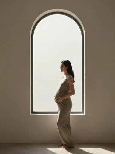 Cinematic portrait of an expecting mother standing by a tall minimalist arched window, soft directional morning light casting gentle shadows, clean architectural interior, muted earthy tones.