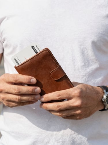 Close-up of a traveler's hands holding a leather boarding pass wallet and a luxury watch, clean composition, natural side light, 35mm lens