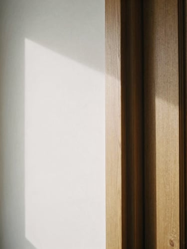 Tight architectural detail shot, soft side lighting, custom oak door frame meeting a plaster wall with a perfect shadow gap reveal.