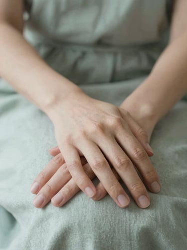 A close-up of hands resting calmly on a soft linen lap, warm natural light, shallow depth of field, serene editorial style.