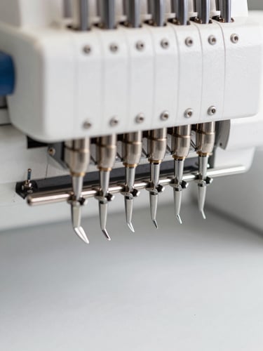 Extreme close-up of a high-speed multi-head embroidery machine needle area, bright neutral studio lighting, focus on metallic textures of the needle bar and tensioners, clean white background.