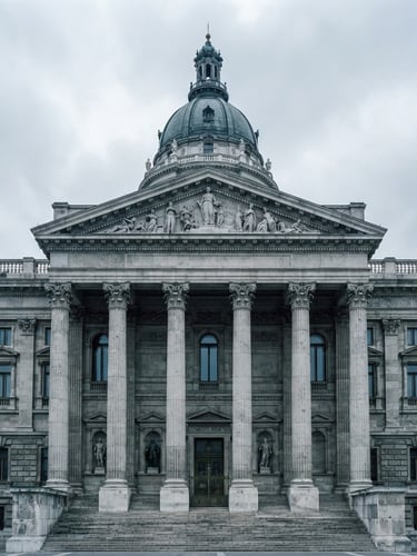 Wide architectural crop of a neoclassical legislative building facade, desaturated cool tones, overcast natural daylight, sharp focus, high contrast, 35mm