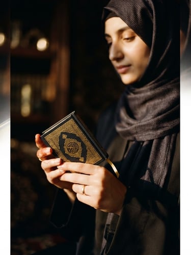 Close-up portrait of a serene, veiled woman's hands gently holding a small, intricately designed Quran, warm golden light filtering from the side, luxurious dark editorial photography, deep black and gold tones, soft shadows, 35mm lens