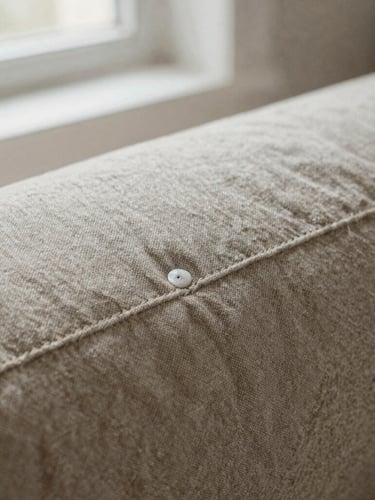 Tactile close-up of heavy organic linen fabric, double-needle stitched seams, soft north-facing window light, muted earthy tones, medium format film