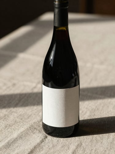 Wine bottle with a minimal paper label on a raw linen cloth, cellar ambient light casting long shadows across the surface