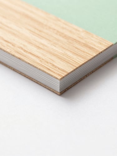 Macro close-up of sustainable materials, textured light oak wood grain meeting brushed recycled aluminum, warm natural daylight, soft focus
