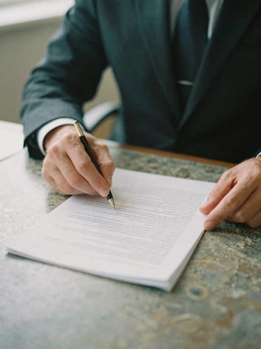 Close-up of a solicitor's hands reviewing physical legal documents on a polished desk, soft overcast British daylight, muted forest green and stone tones, 35mm film grain