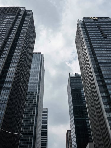 Low-angle architectural shot of Jakarta's SCBD financial district towers, sharp geometry, overcast daylight, deep dramatic shadows, high-contrast.
