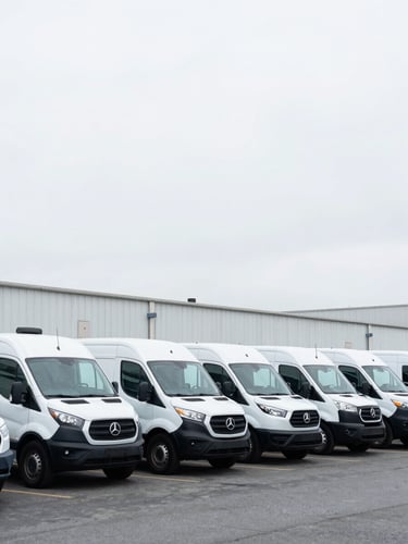 A clean exterior shot of commercial transport vehicles parked in an organized industrial yard under bright overcast Washington sky.