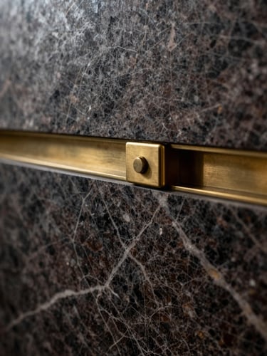 Moody architectural close-up of premium dark veined marble and a brushed brass joint, high-contrast chiaroscuro lighting, elegant and precise.