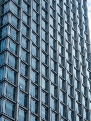 Abstract architectural lines of a modern corporate skyscraper facade, cool blue daylight, crisp sharp angles, minimal composition.