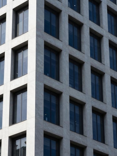 Tight architectural crop of a modern corporate building facade, sharp angles, cool diffused daylight, deep navy shadows, high contrast