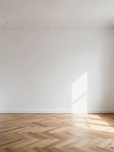 Straight-on architectural shot of a minimalist Parisian living room with flawless white walls, high ceilings, and herringbone oak flooring, bathed in soft morning light.