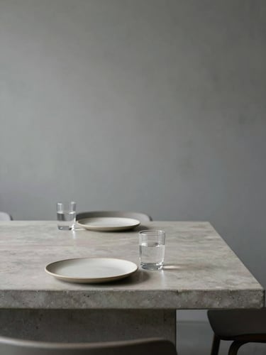 Empty minimalist tasting room, long pale concrete table with two ceramic plates and a glass of water, no people, soft north-facing diffuse light, slate-grey wall background
