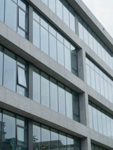 Abstract architectural details of a modern medical facility with clean glass panels and cool daylight, sharp focus.