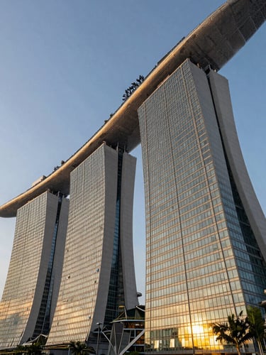 Low angle architectural perspective of Singapore Marina Bay financial towers during golden hour, sharp geometric lines of glass and steel reflecting warm light, negative space on the left.