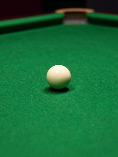 Macro shot of a pristine green billiard table, a single white cue ball in sharp focus, moody Rolex green ambient lighting, cinematic 35mm photography