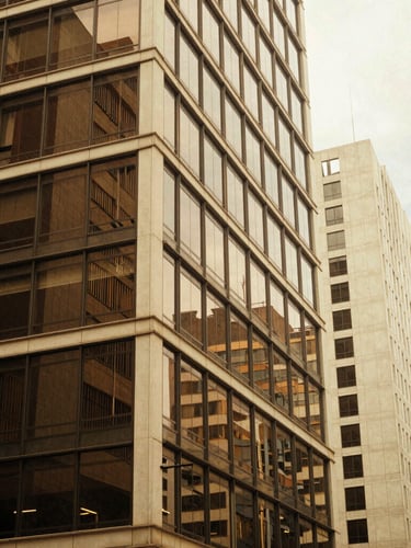 Architectural abstract of a modern Colombian business district in Bogotá, warm afternoon window light reflecting on glass, espresso and cream tones, 35mm